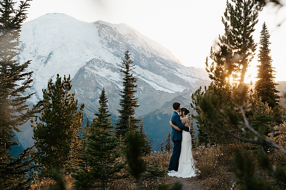 Groom holding bride along a hiking trail at Sunrise, Mt Rainier after their private sunset vows. 