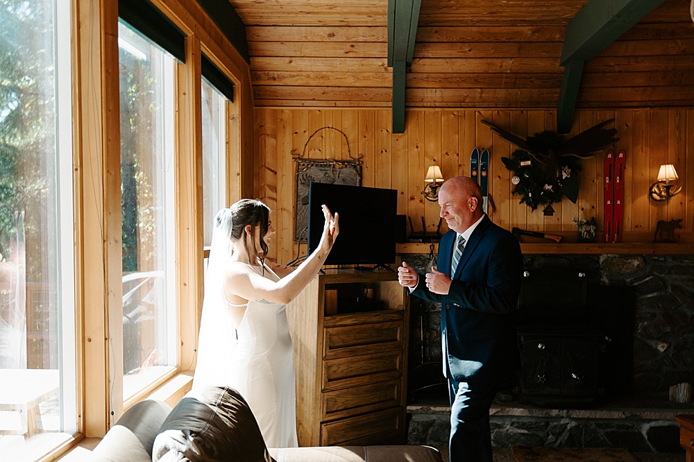 Bride raising her hands in excitement with her dad walking towards her for their first look!