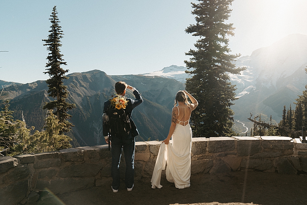 Bride and groom standing at an overlook of Mount Rainier at Sunrise.