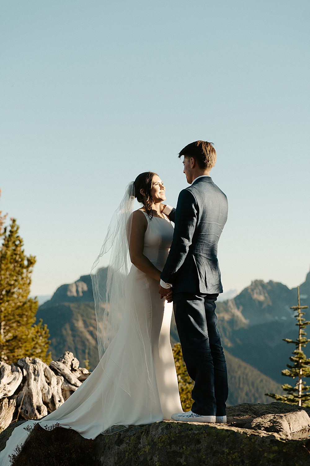 Bride and groom standing on a rock facing each other in Mount Rainier National Park.