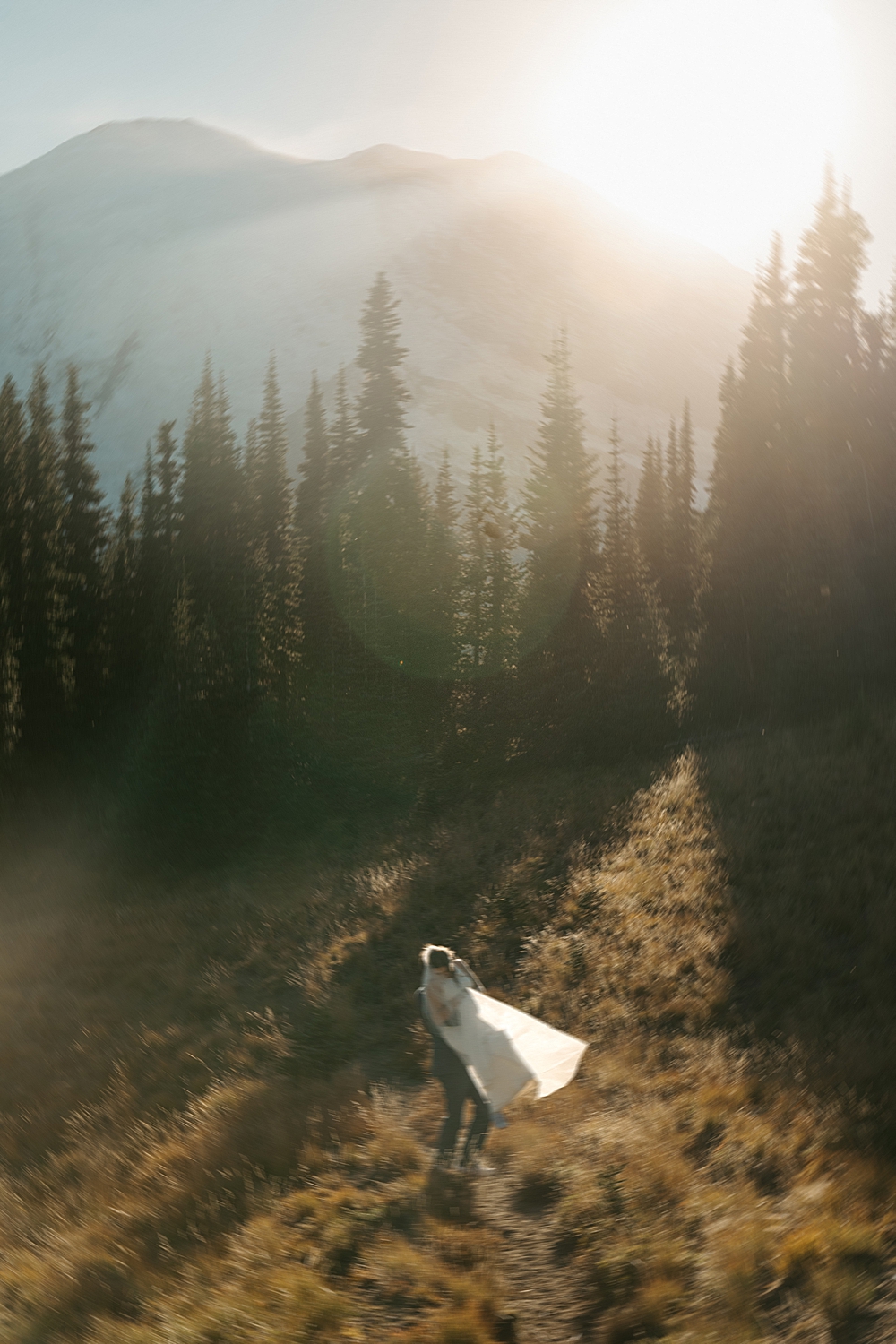 Blurry photo of a groom spinning his bride on a trail in Mount Rainier at sunset.