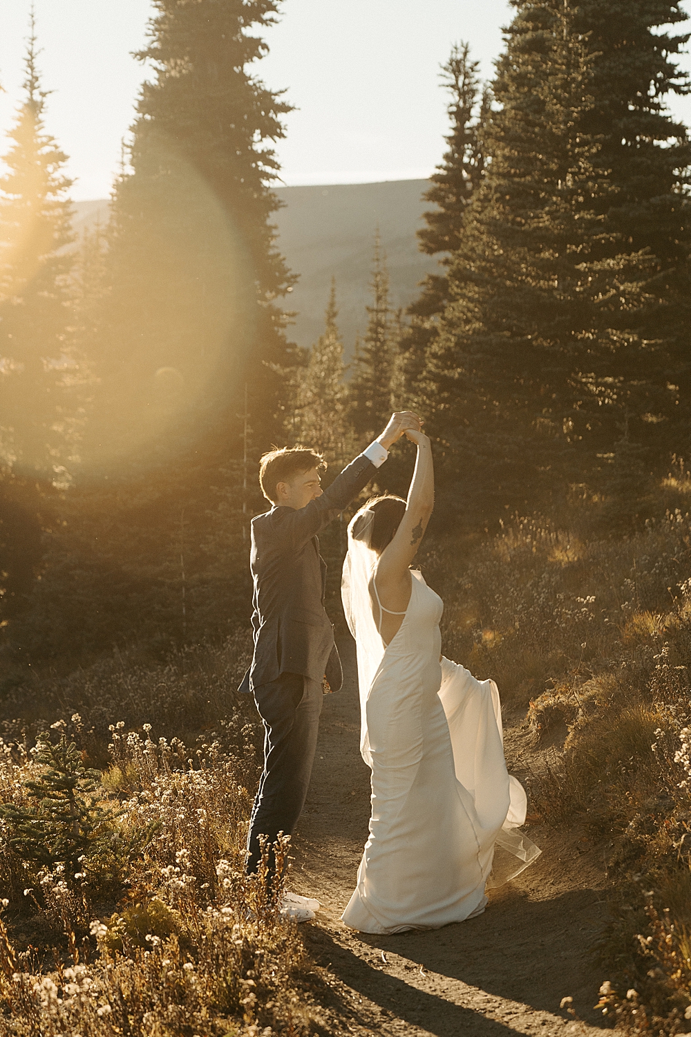 Golden hour photo of groom spinning his bride on a trail at Mount Rainier.