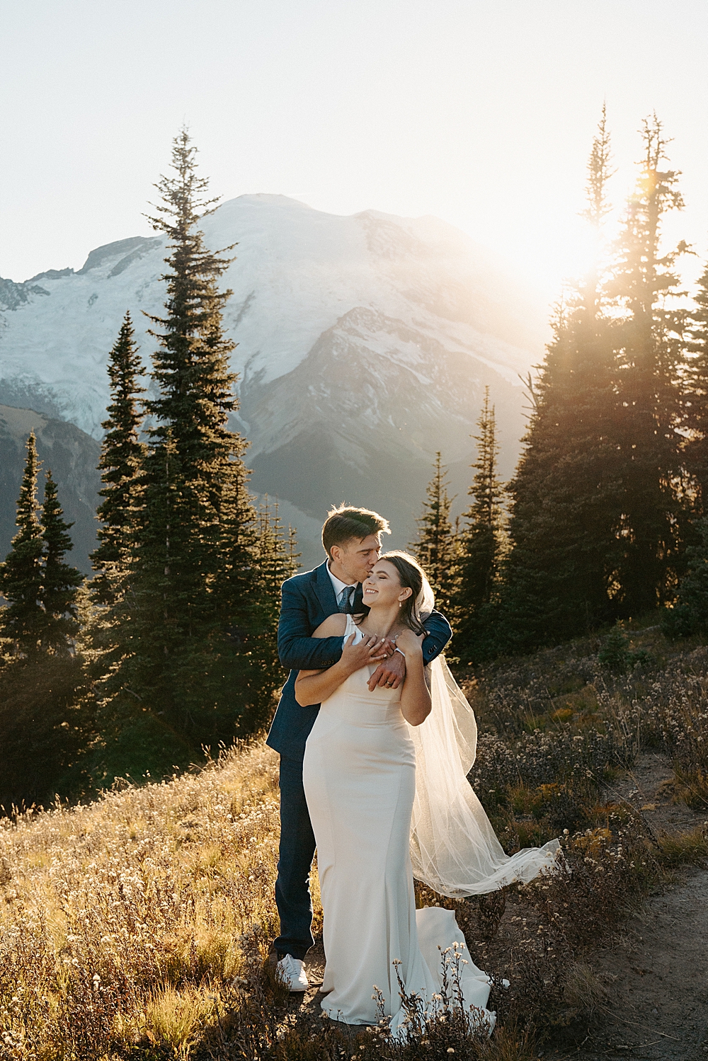Mount Rainier elopement photo of groom holding his bride in front of him on a trail in the park.