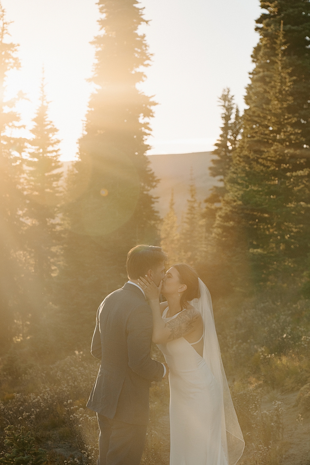 Bride and groom kissing after saying private vows along a trail at Mount Rainier during golden hour.