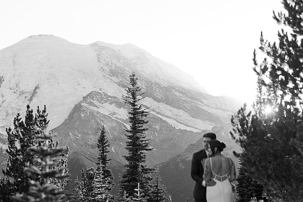 Black & white blurry photo of bride and groom with Mount Rainier in focus.