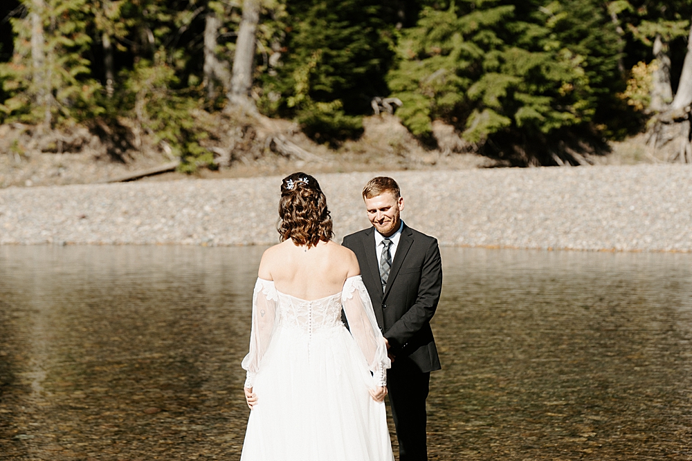 Bride and groom sharing a first look at their elopement along Avalanche Creek in Glacier Park captured by Venture to Elope, a Montana photo & video team. 