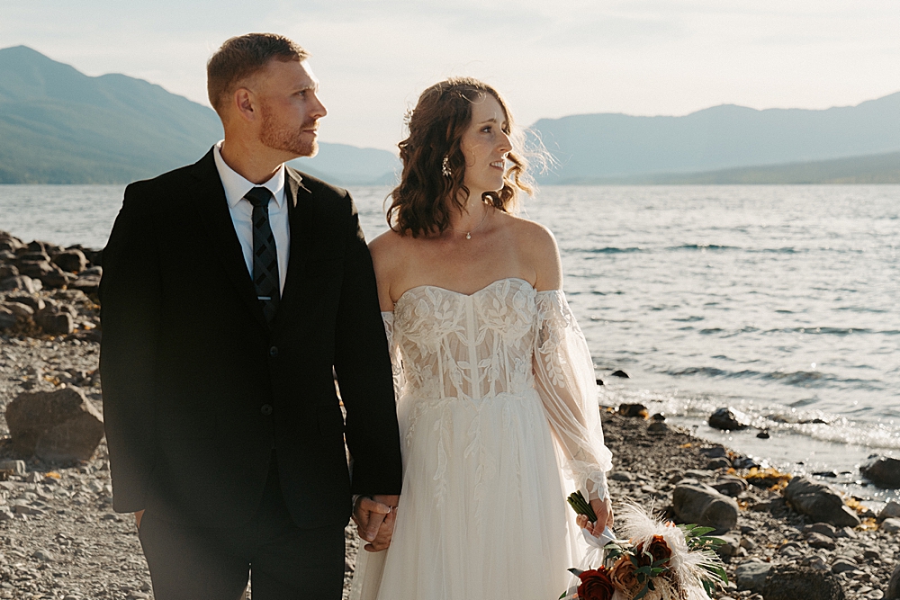 Up close of bride and groom facing the water at sunset along Lake McDonald
