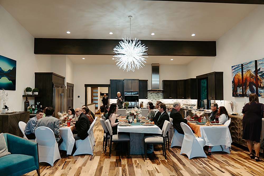 Whitefish rental reception dinner with guests sitting at three decorated tables in a living room
