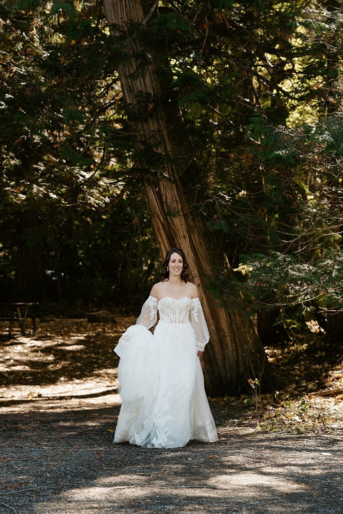 Bride holding her train and walking in the shade