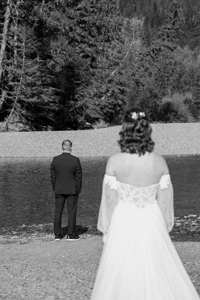 Black and white of bride walking to the groom for a first look along Avalanche Creek