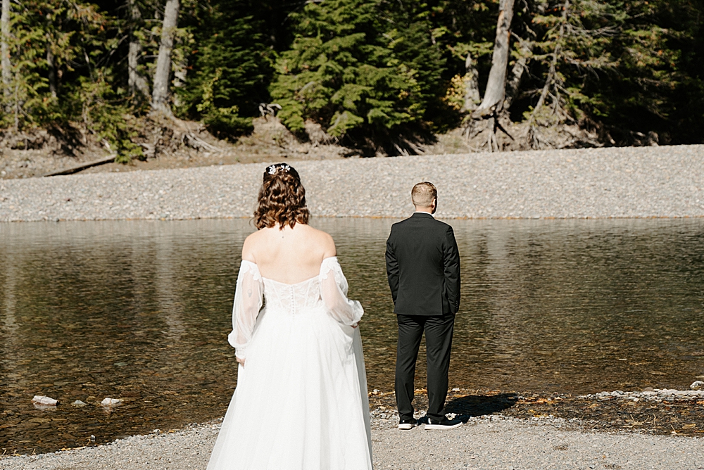 Bride walking to groom along Avalanche Creek for a first look
