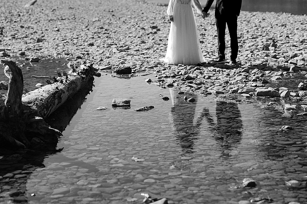 Bride and groom holding hands with their reflection in the water