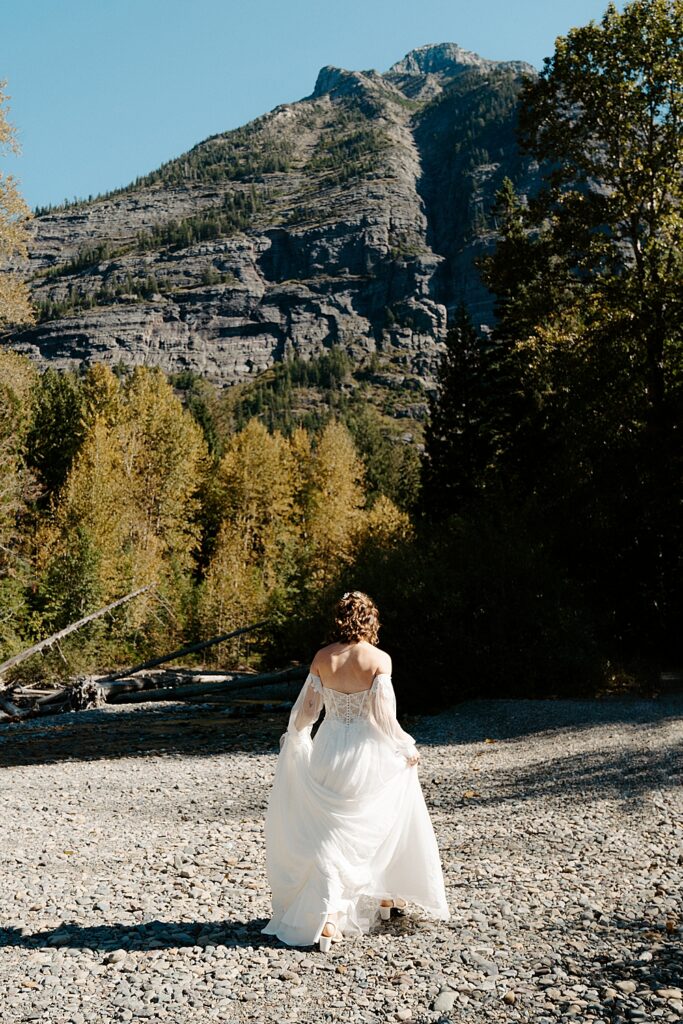 Bride holding her train and walking at Avalanche Creek Picnic Area