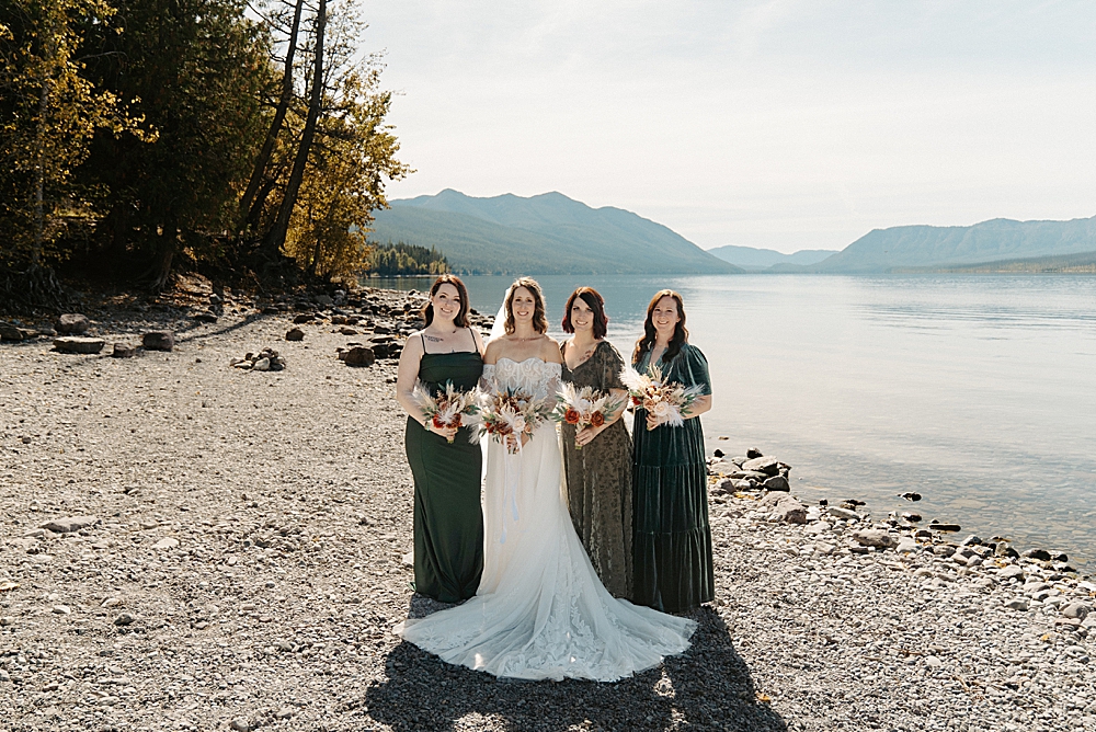 Bride and three bridesmaids in forest green dresses with dried floral bouquets