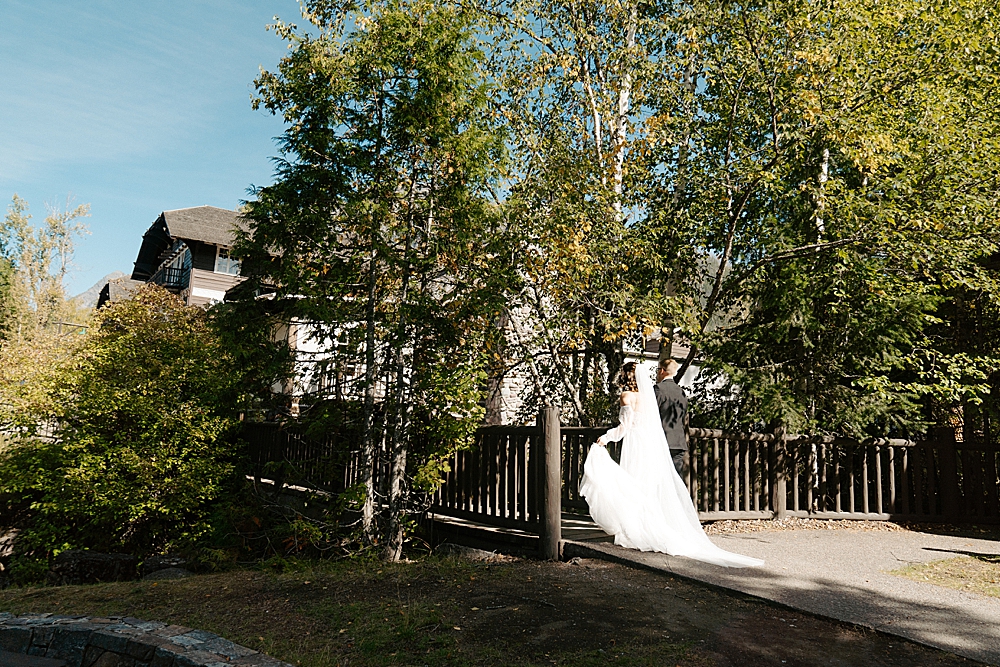 Bride and groom walking across bridge at Lake McDonald Lodge