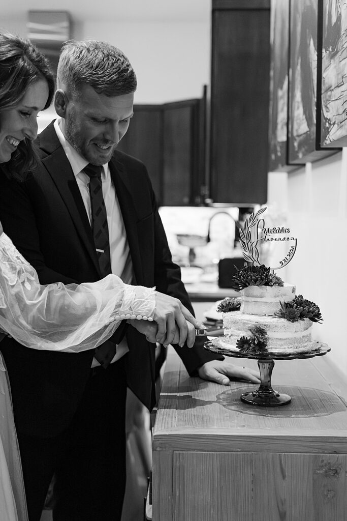 Black and white of a bride and groom cutting into their wedding cake