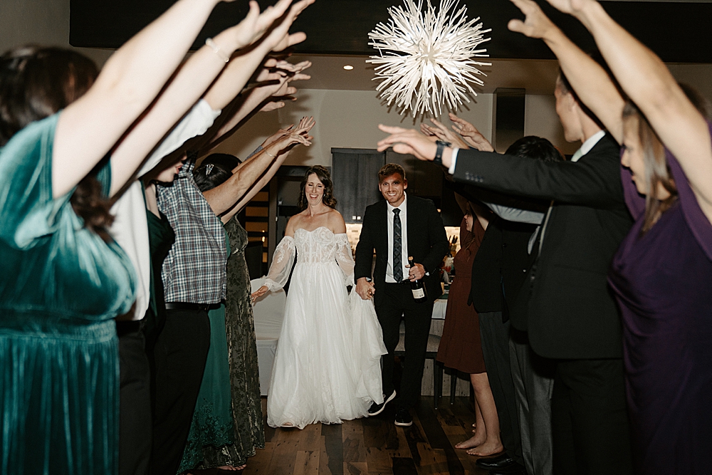 Bride and groom running under a tunnel created by their wedding guests at the reception