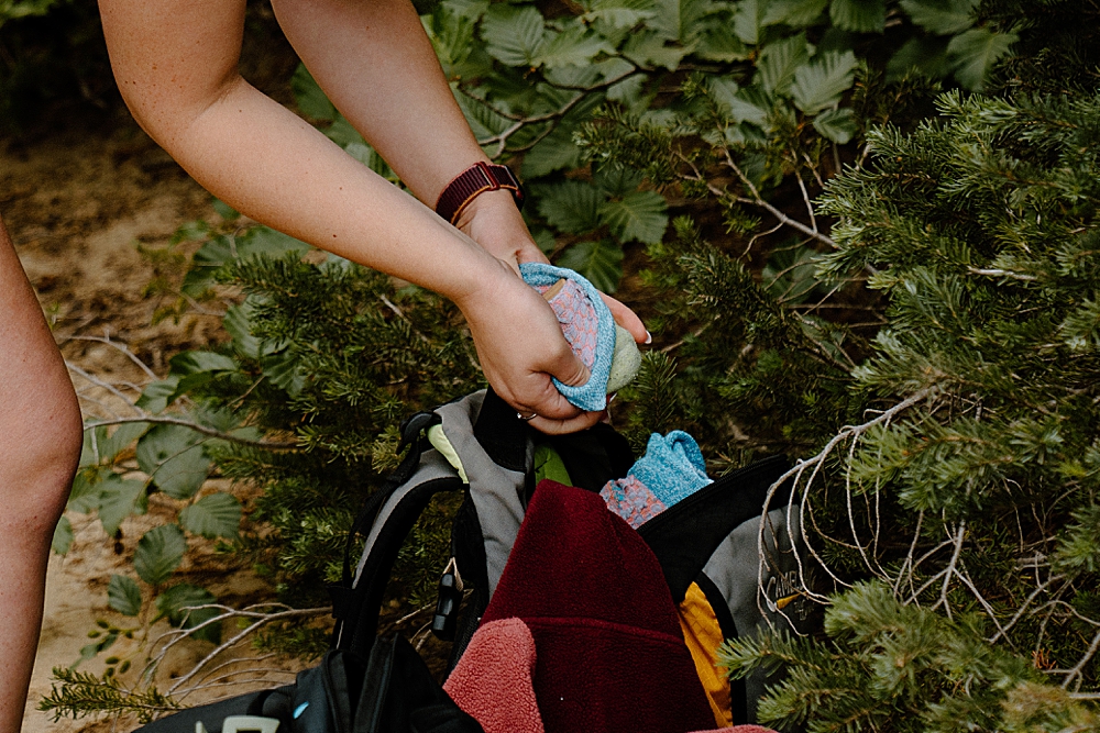 Up close of hands unwrapping a ring box from a bundle of socks to propose along a hiking trail at Mount Rainier.