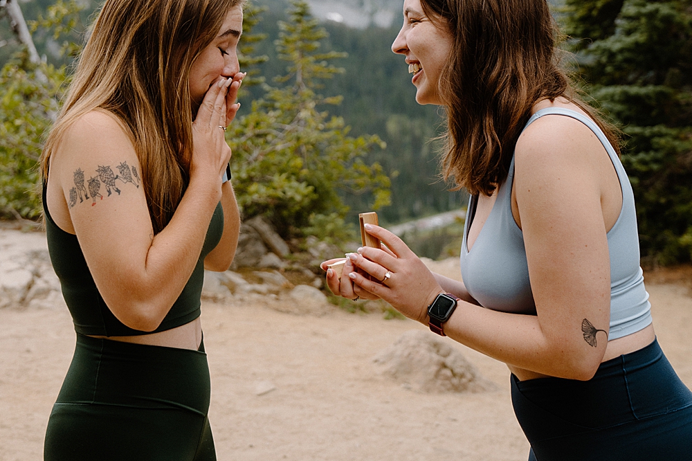 Up close of one girl in hiking attire proposing to her girlfriend on a hiking trail at Mount Rainier.