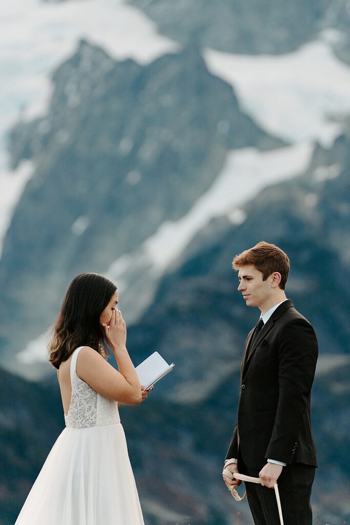 Bride wiping a tear while saying private vows to her groom at their sunrise Mount Baker elopement.