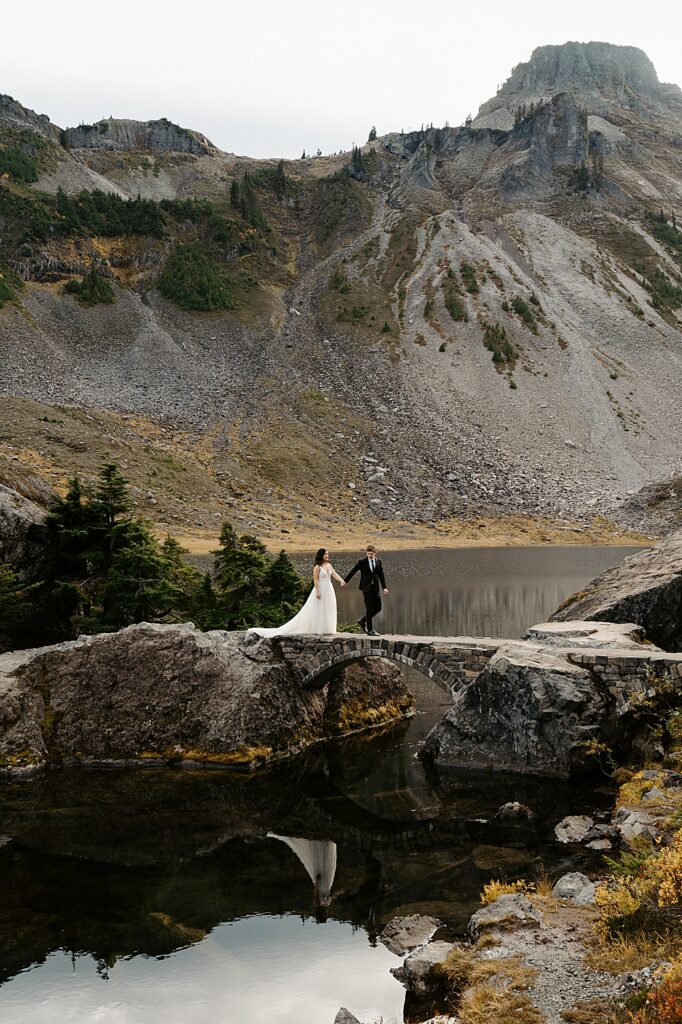 Bride and groom walking on a stone bridge for their Bagley Lakes elopement in Mount Baker-Snoqualmie National Forest. 