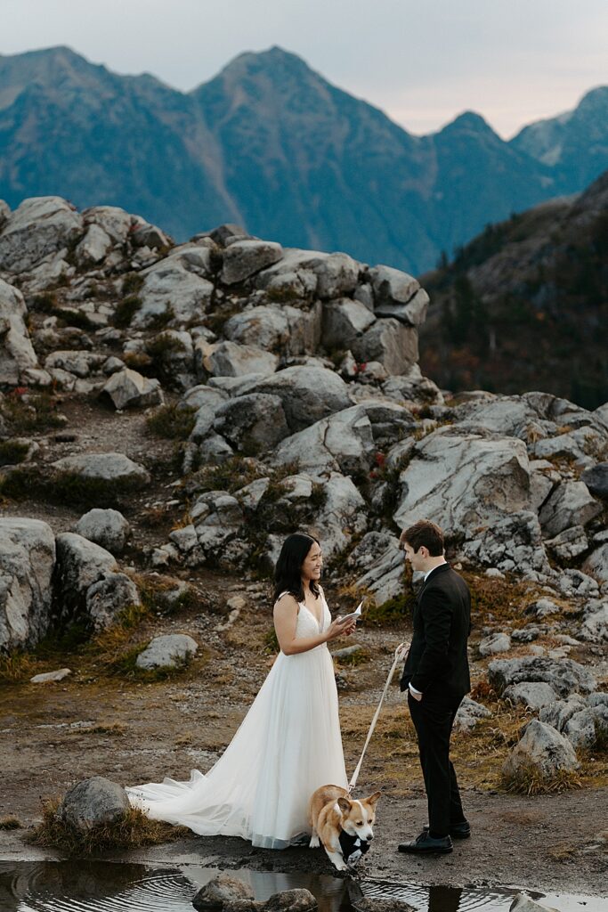 Sunrise Mount Baker-Snoqualmie National Forest elopement with bride saying vows to groom and their leashed corgi next to them.