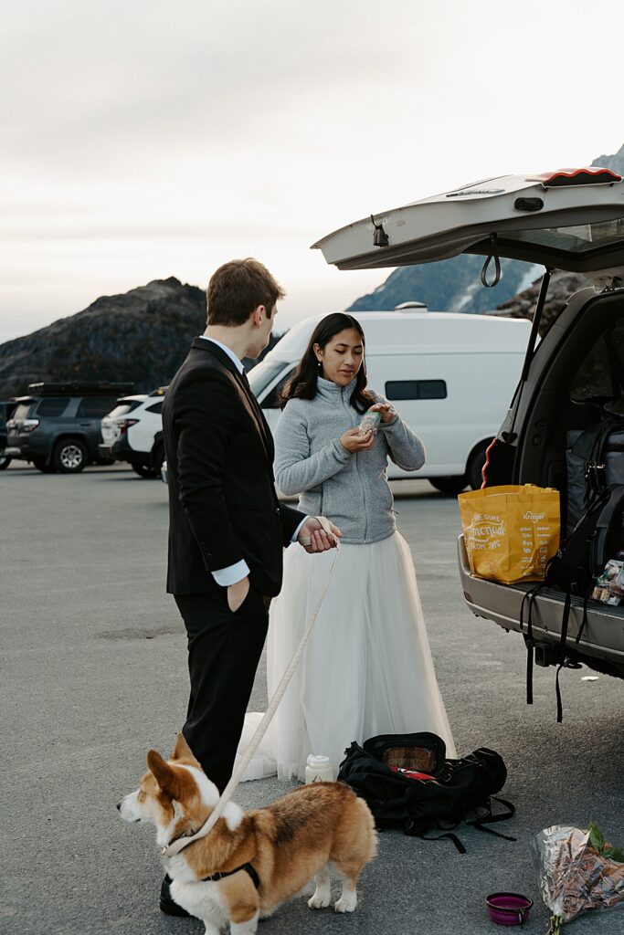 Bride and groom with their corgi getting snacks from the back of the car after their sunrise elopement ceremony in Washington.