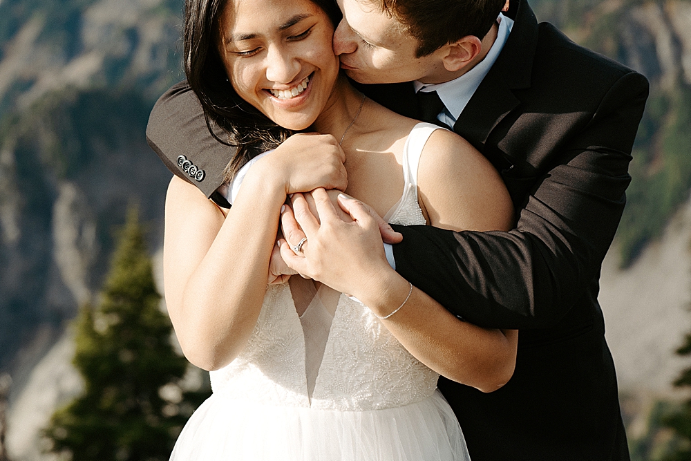 Up close of groom kissing bride on the cheek.