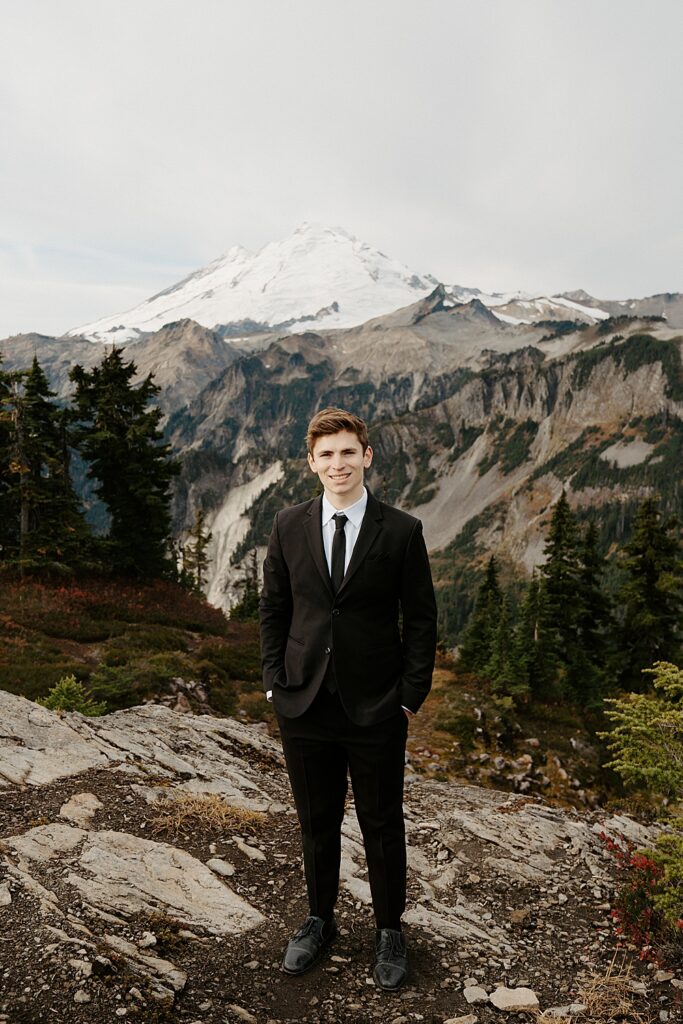 Groom portrait in a black suit with Mount Baker in the background.