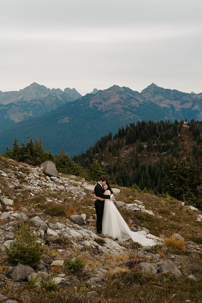 Bride hugging groom while standing on a trail after their sunrise Mount Baker elopement.