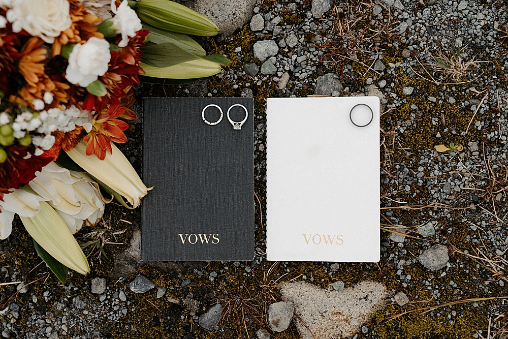 Black & white vow books, wedding rings, and fall bridal bouquet.