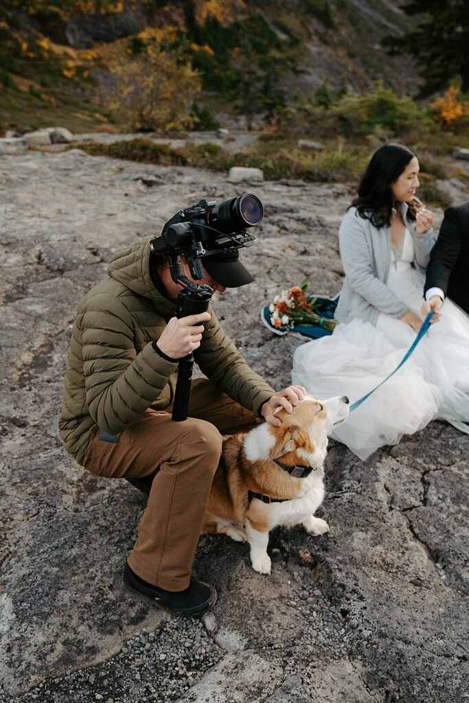 Venture to Elope's videographer petting a corgi pup at a couple's fall elopement with his video equipment in one hand.