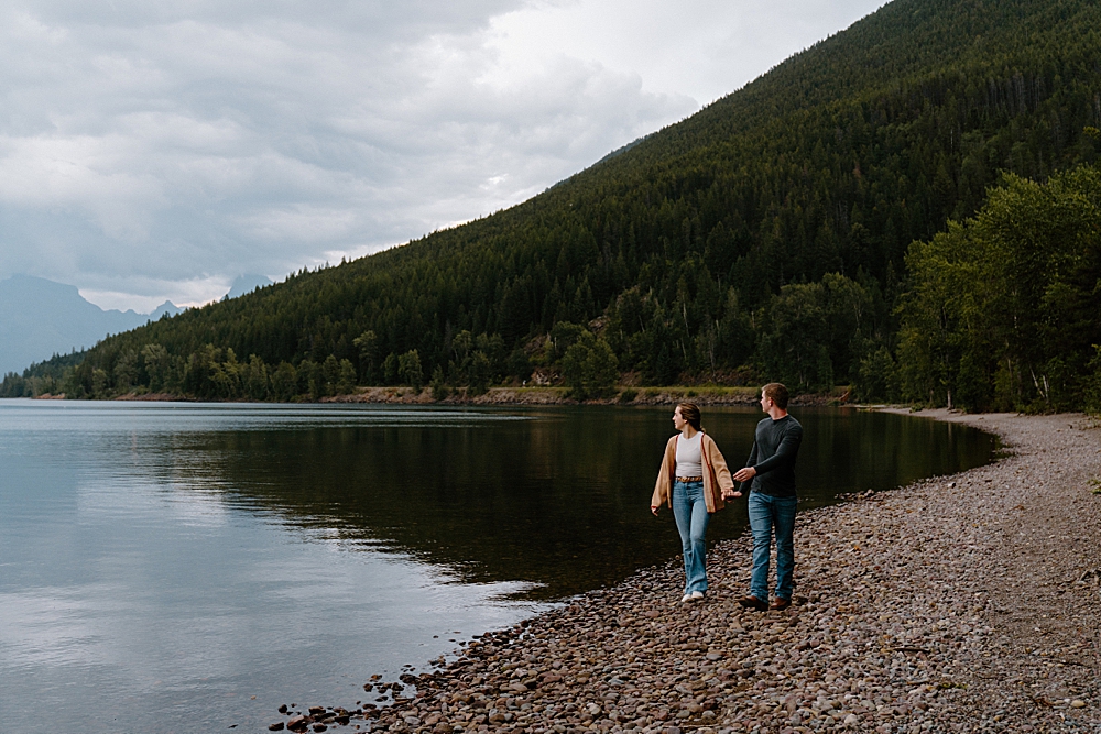 Couple holding hands walking on Apgar Beach after surprise Glacier proposal