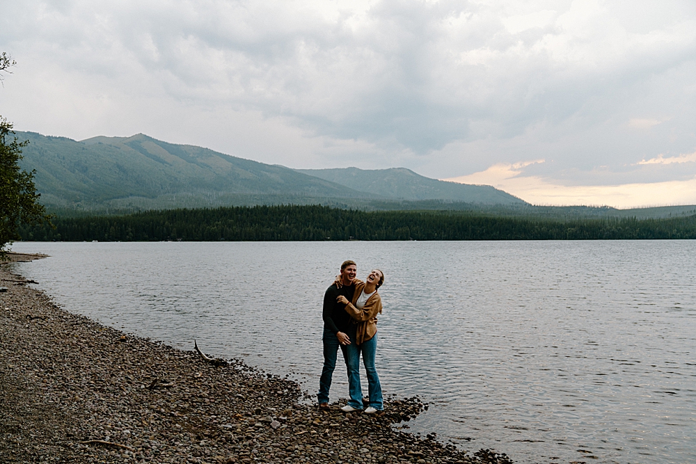 Couple holding each other and laughing on Lake McDonald for engagement session