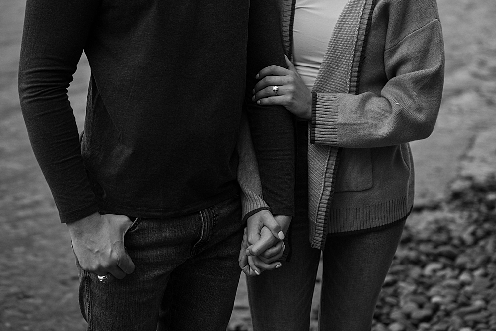 Black & white of couple holding hands and girl showing her new engagement ring