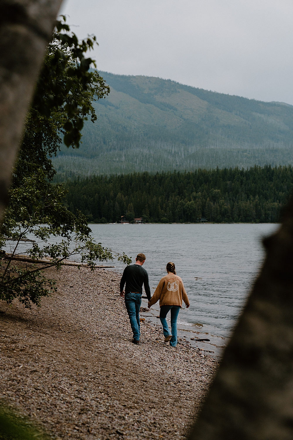 Couple walking on the rocky shore of Lake McDonald for their Montana engagement session