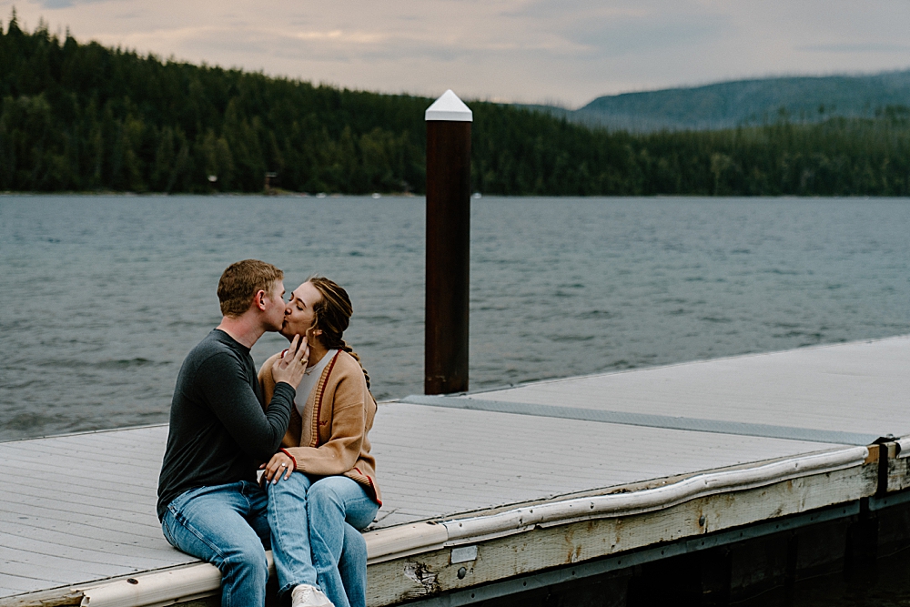 Couple kissing and sitting on a dock at Apgar Beach in Glacier Park