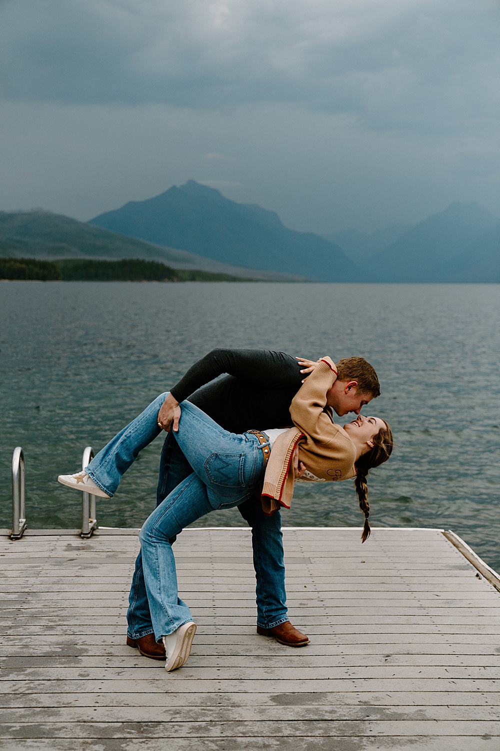 Couple dipping on the dock at Apgar Village for their moody evening engagement session in Glacier Park