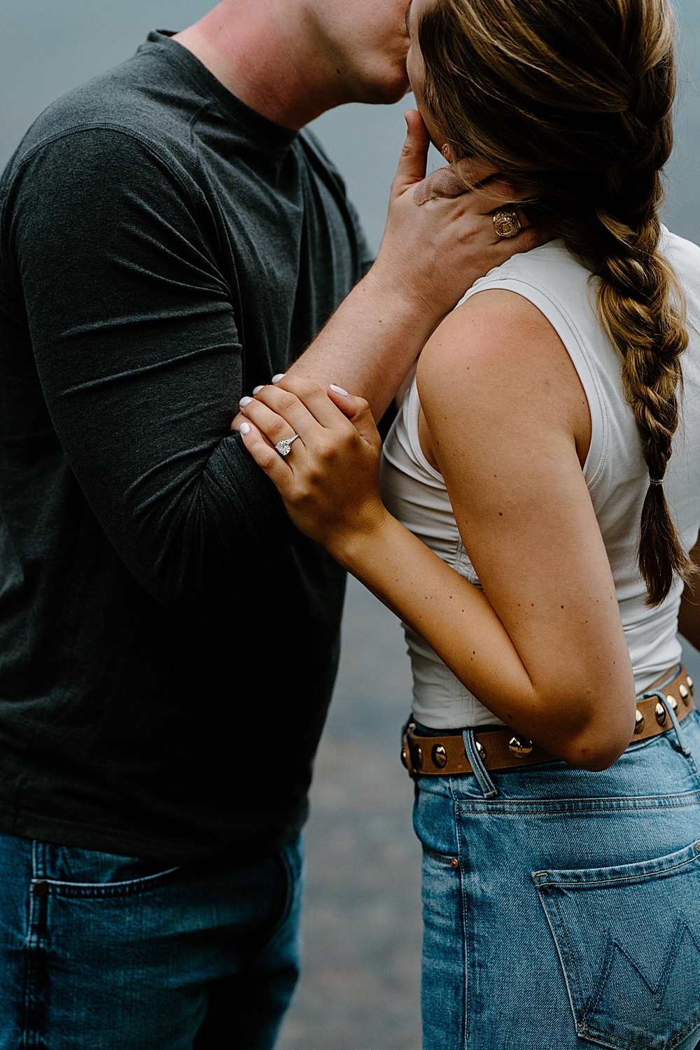 Up close of couple kissing and fiancée holding her man's arm to show off her new engagement ring