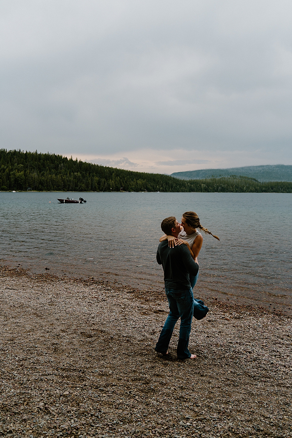 Engagement photo at Lake McDonald with guy holding and spinning his fiancée