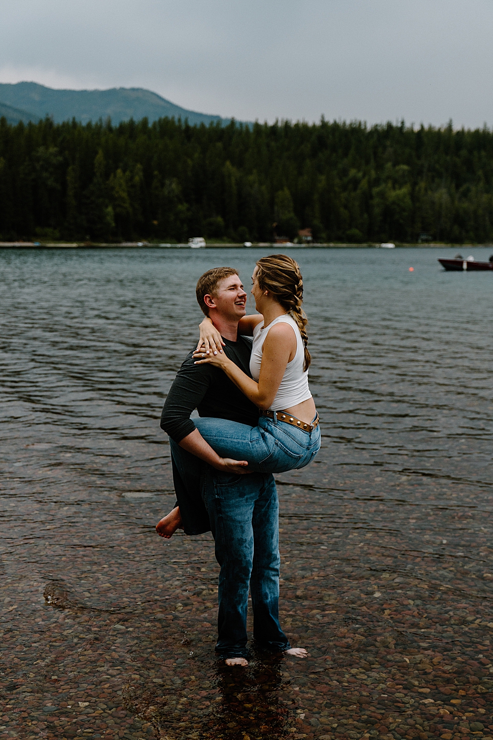 Guy holding his fiancée with her legs wrapped around him while he's standing barefoot in the water