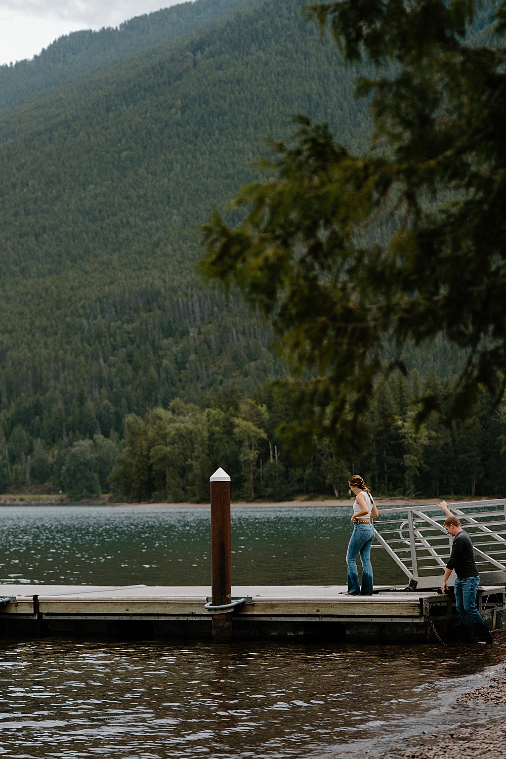 Girl standing on Apgar dock with her fiancé getting onto the dock behind her