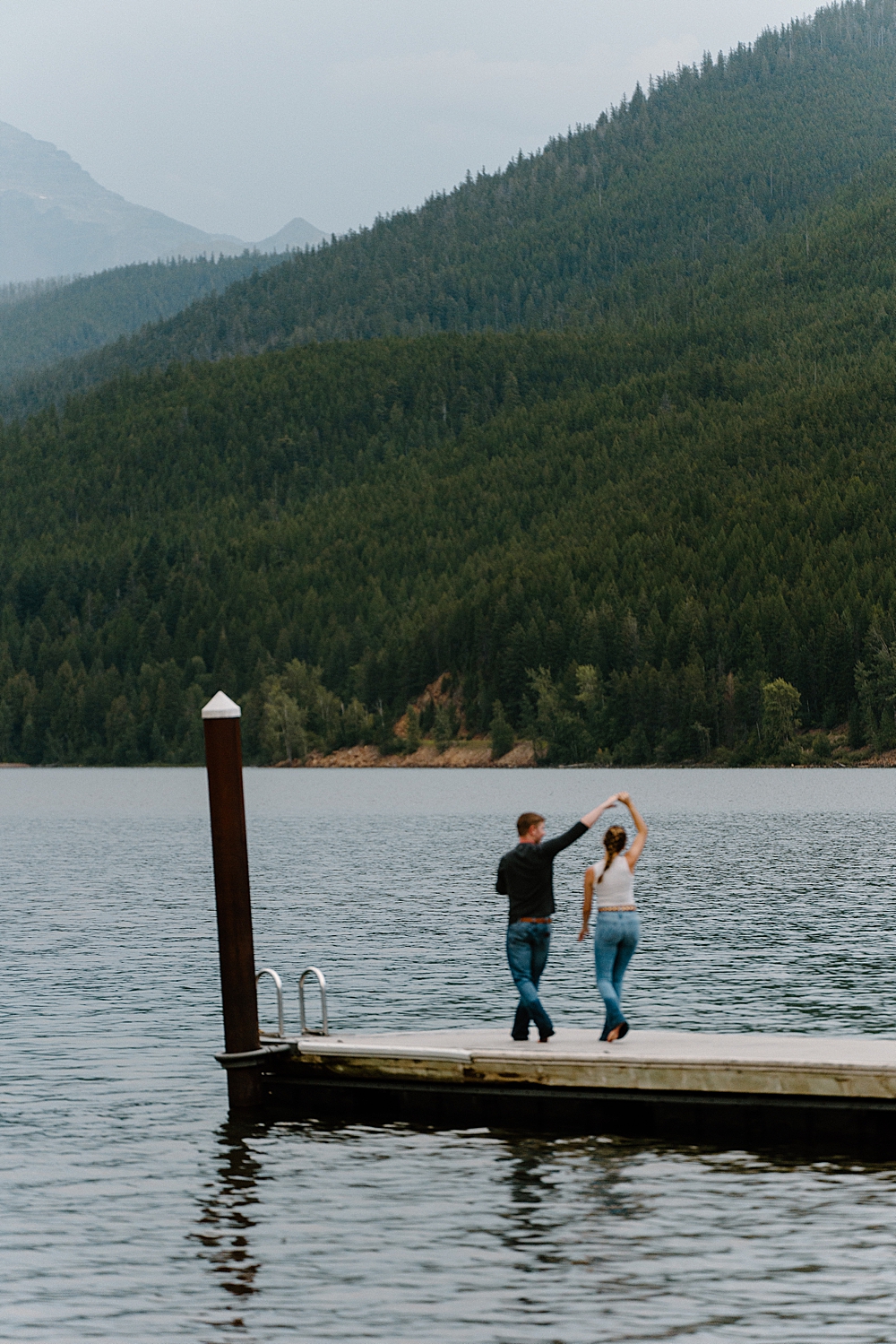 Couple swing dancing on dock at Apgar Beach for their Lake McDonald engagement session in Montana
